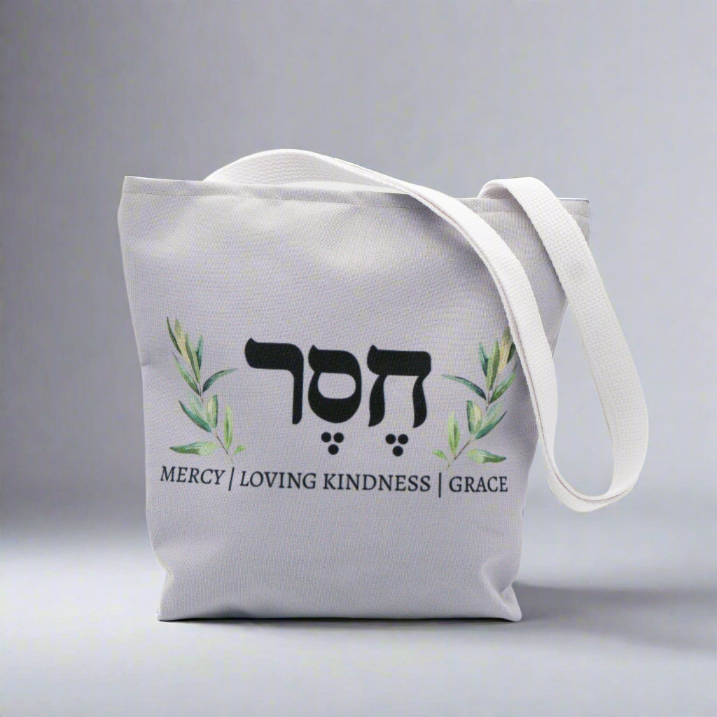 Gray tote bag with Hesed writing and definition surrounded by Olive Branch with Hebrew writing.