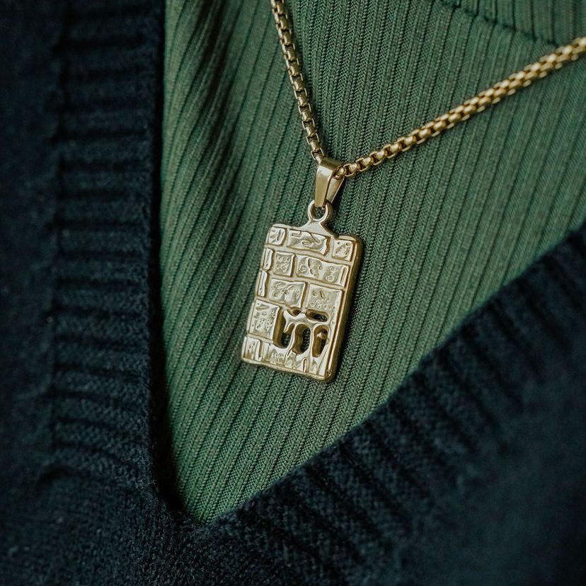 Gold western wall necklace pendant with chai symbol in Hebrew on a green sweater