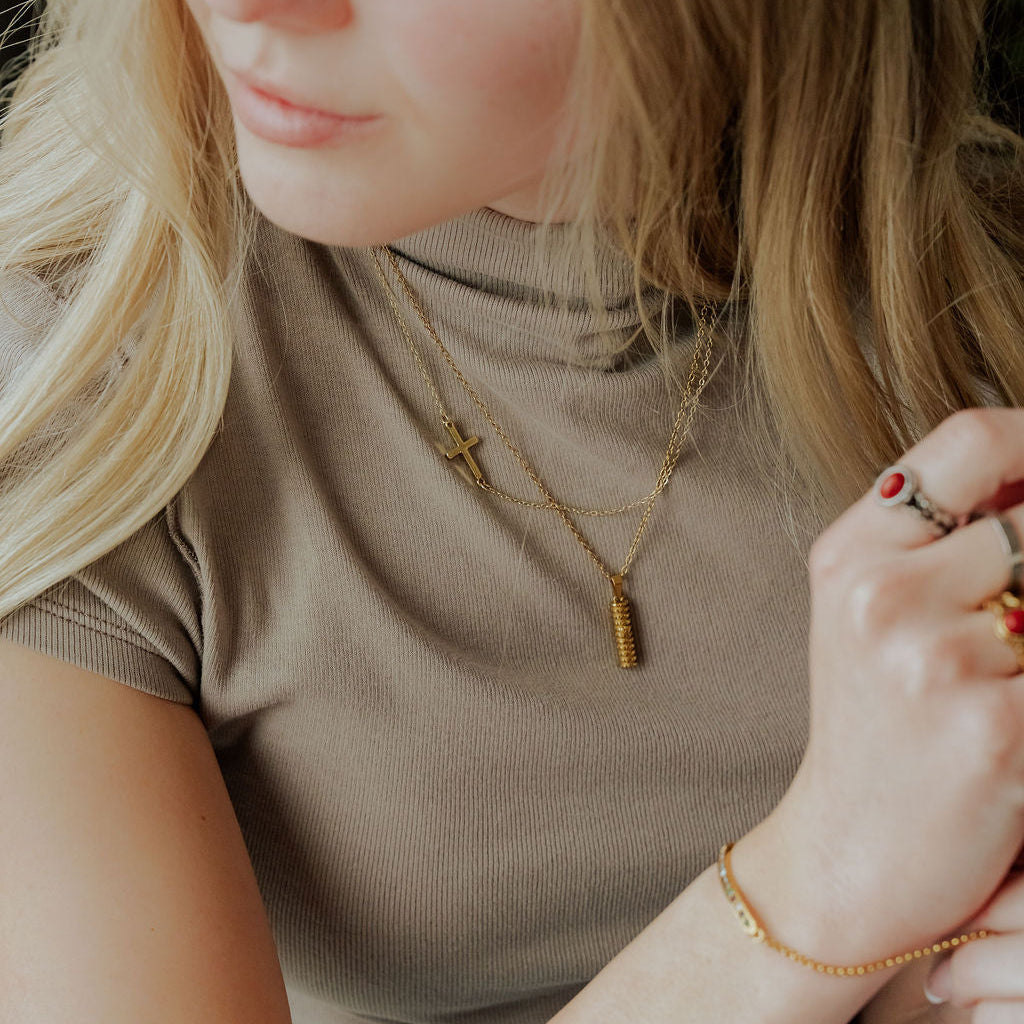 Silver Mezuzah necklace featuring the Shin symbol over the Western Wall design displayed on model layered with cross necklace.